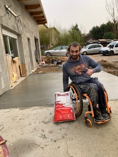Benoit-fayolle-vicat_IMG_3946 Benoit fayolle en fauteuil devant la terrasse en béton construite de ses mains grâce au don de ciment Vicat